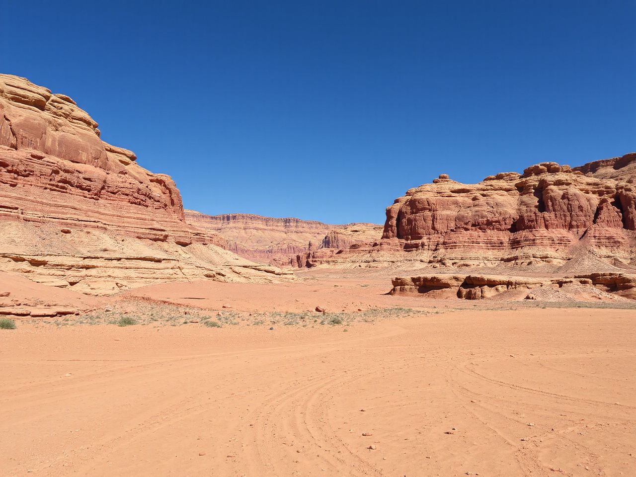 A sprawling desert landscape with layered red rock formations under a clear blue sky