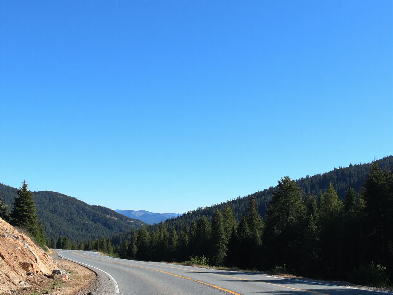 A winding mountain road disappearing into dense forest under a bright blue sky, illustrating transient outdoor locations