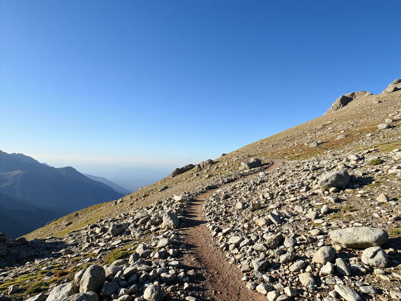A rugged mountain path marked by cairns under clear skies, symbolizing the impact of GPX navigation on hiking