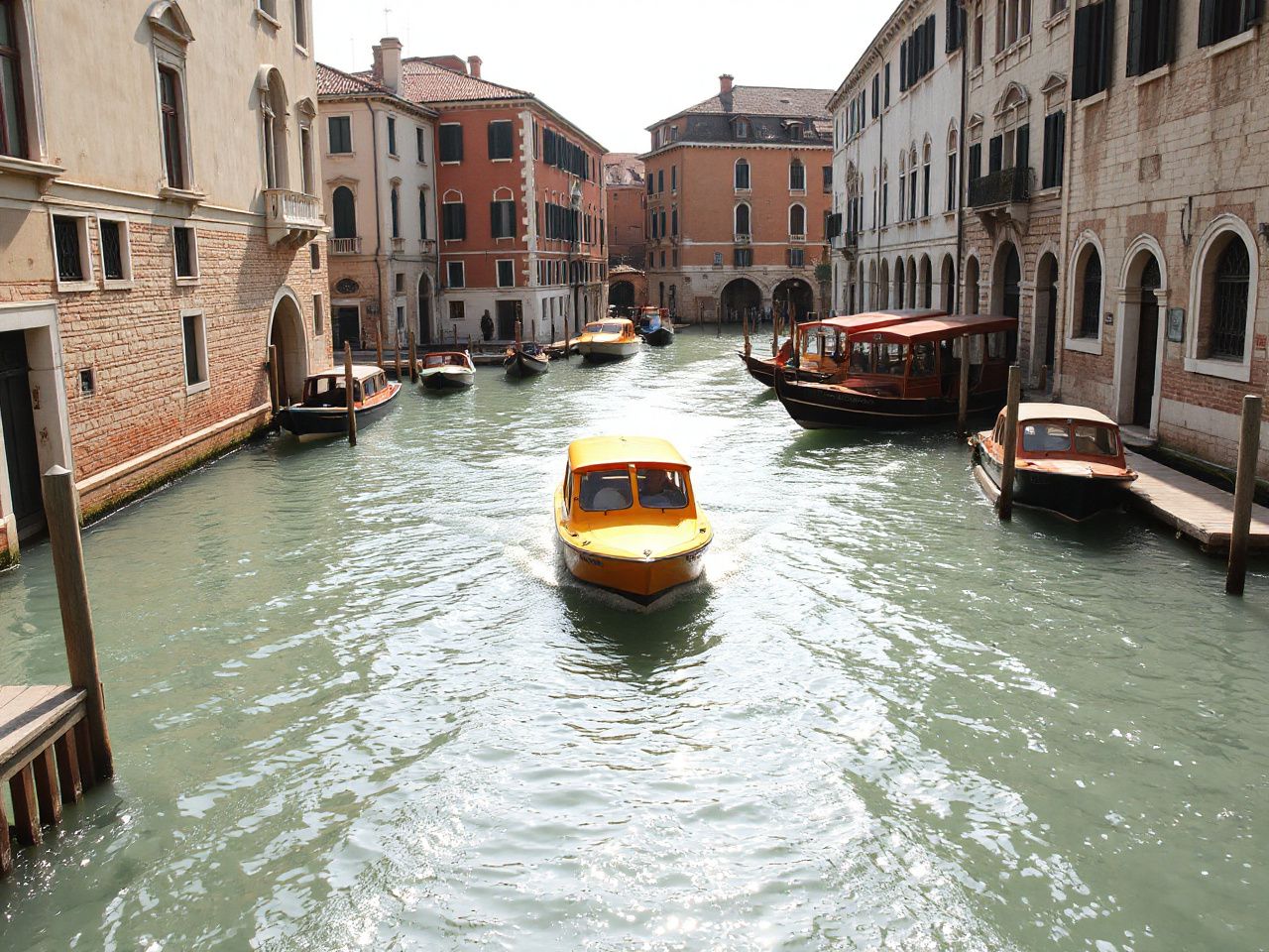 A sunlit Venetian canal with colorful water taxis gliding between historic stone buildings and wooden docks