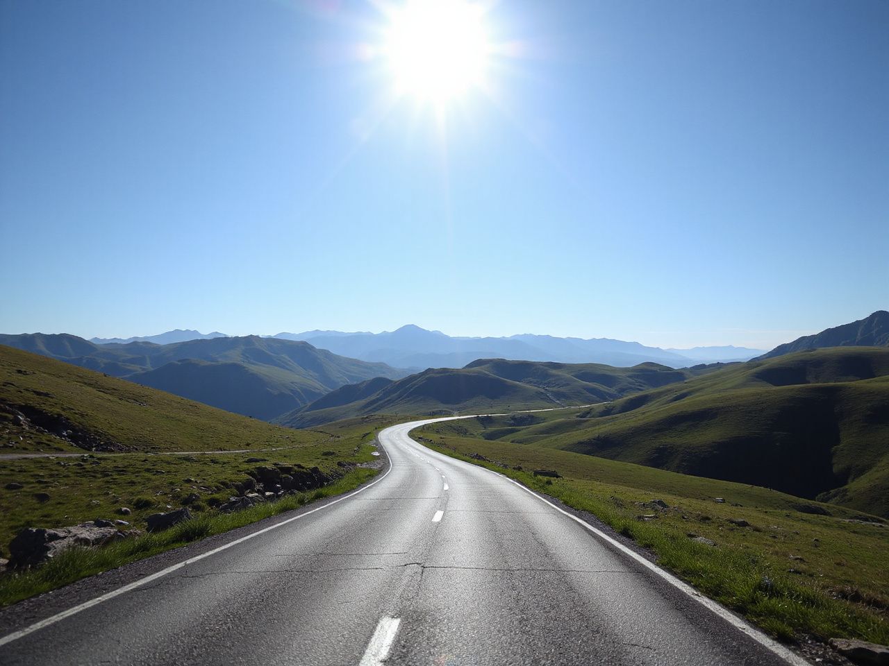 Sunlit mountain road winding through green hills under a clear blue sky, illustrating travel duration concepts