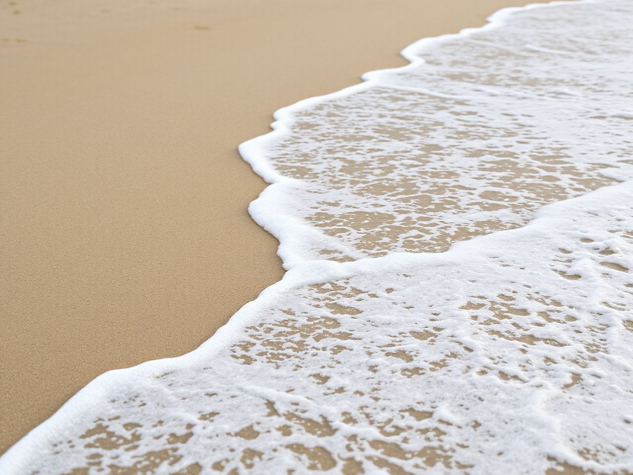 Sandy beach shoreline with gentle waves lapping, highlighting peaceful solitude and the unpredictability of nature