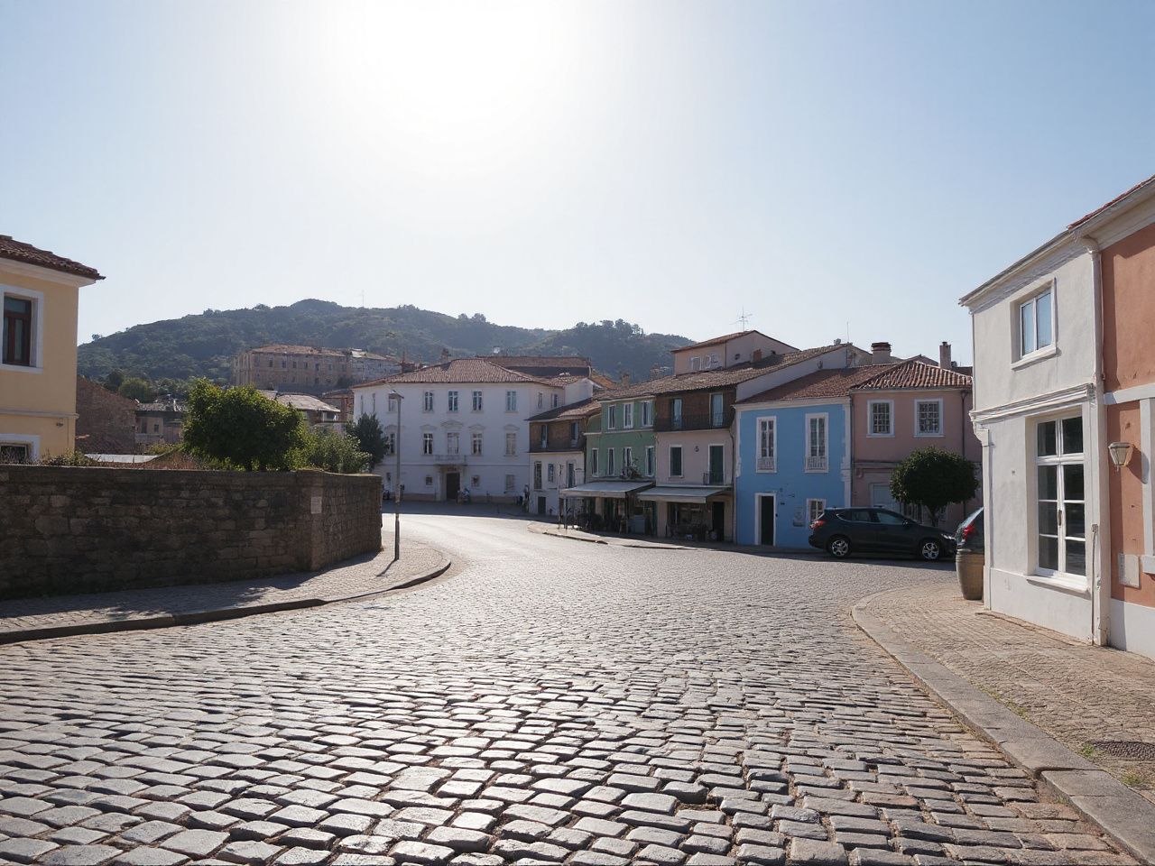 Sunlit coastal town street with cobblestone pavement and colorful buildings under a clear sky