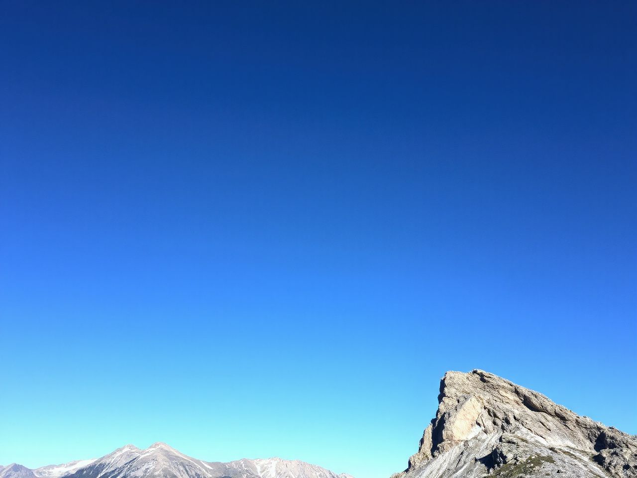 A clear blue sky above a rugged mountain ridge, illustrating natural forces behind adrenaline rushes