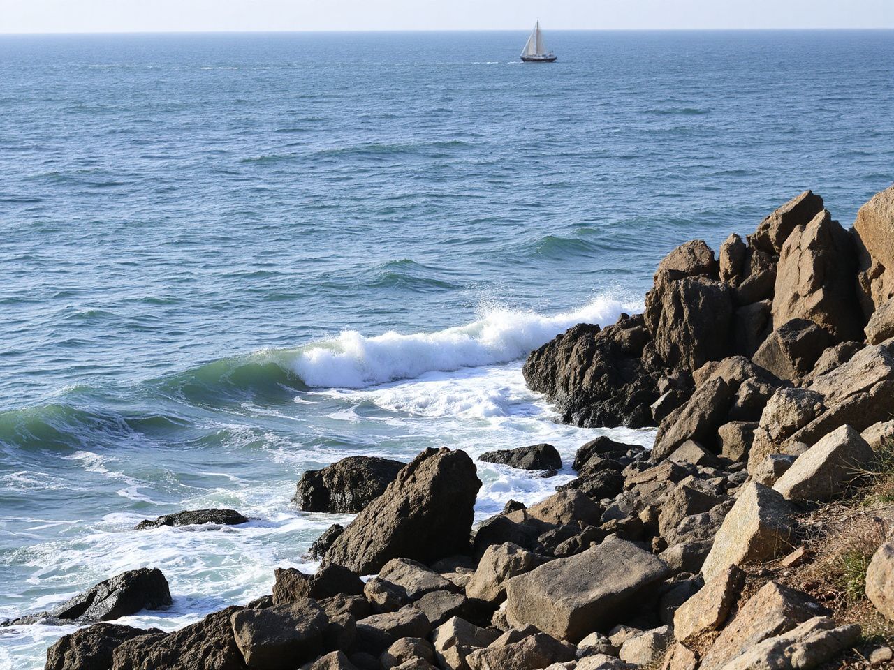 A rugged coastal shoreline with waves crashing against rocks and a distant sailboat on open water