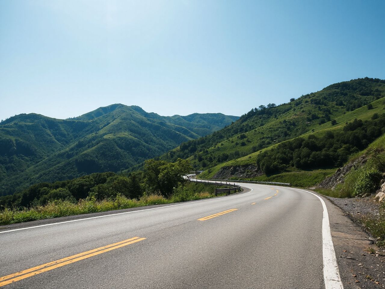 A scenic mountain road winding through lush green hills under a bright blue sky in South Korea