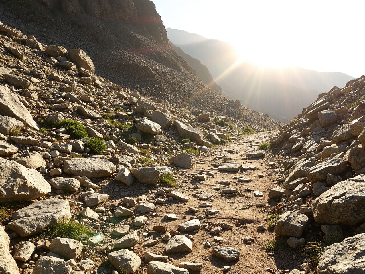 A rugged mountain trail bathed in sunlight, showcasing uneven terrain perfect for testing sneaker outsoles